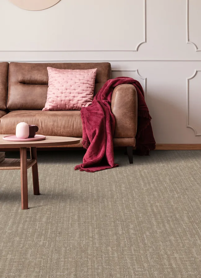 durable brown carpets in a living room with brown leather couch and pink accents